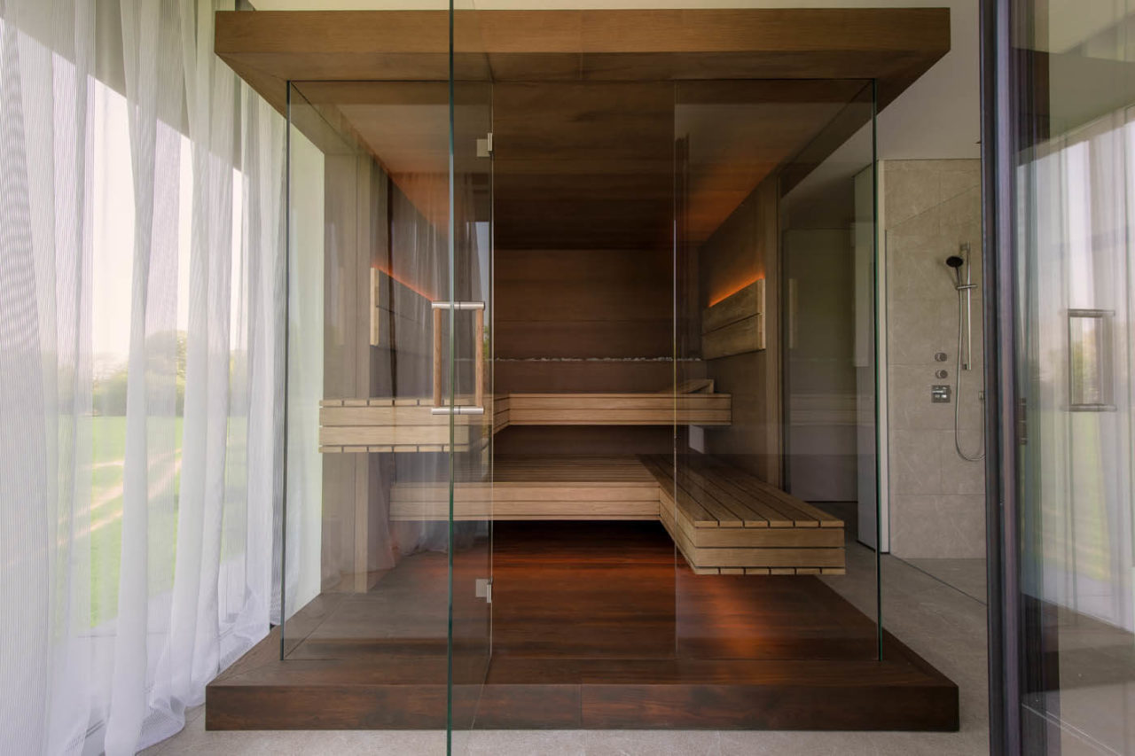 Premium Sauna mit Glasfront im Badezimmer: Dreiseitig verglaste Designsauna als Variation der NIMBUS Sauna mit LED Beleuchtung im Bad.